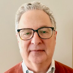 A person wearing glasses and a red sweater, smiling at the camera.