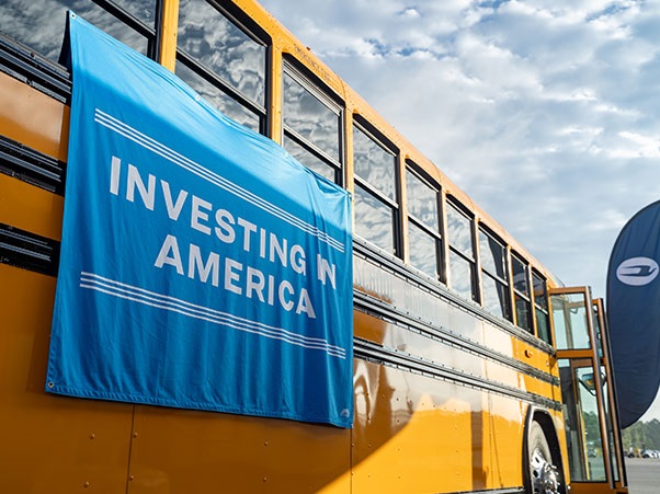 A yellow school bus, with a banner that reads, "Investing in America"