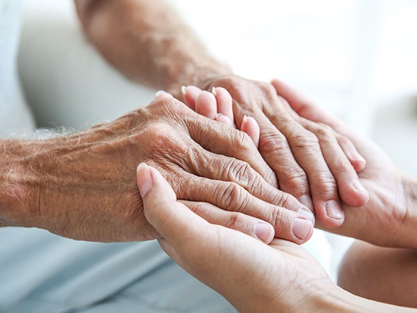 Two pair of hands embracing each other. One pair of hands belongs to an older person.